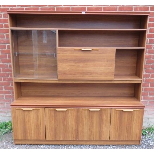 731 - A mid century teak effect wall unit, comprising asymmetrical display shelving with drop down central... 