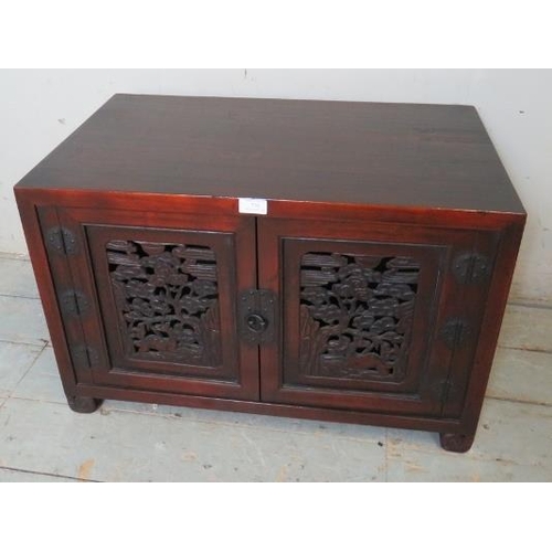 754 - A Korean stained elm low side cabinet with carved & pierced doors depicting foliate motifs, raised o... 