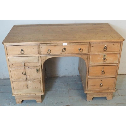 787 - An antique pine kneehole desk, the base having an arrange of six drawers and a cupboard to one side ... 