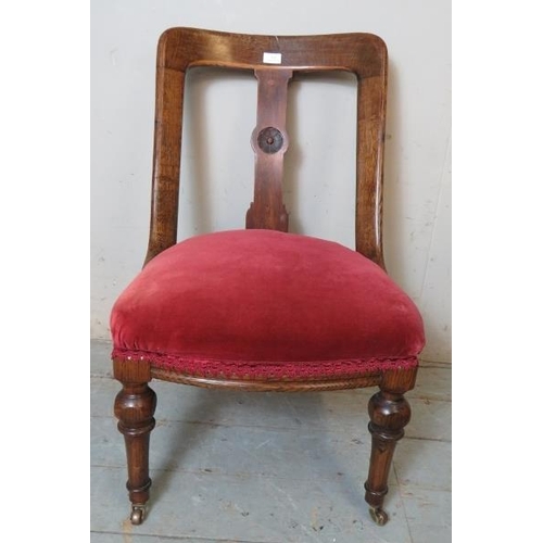 815 - A Victorian oak low bedroom occasional chair with roundel carved back splat raised on tapering turne... 