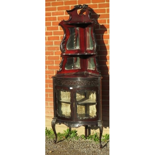 820 - A turn of the century ebonised corner display unit in the Flemish taste, with mirror backed shelves ... 