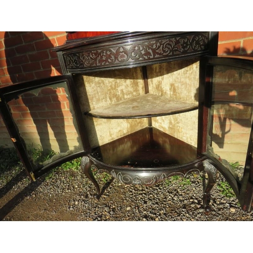 820 - A turn of the century ebonised corner display unit in the Flemish taste, with mirror backed shelves ... 