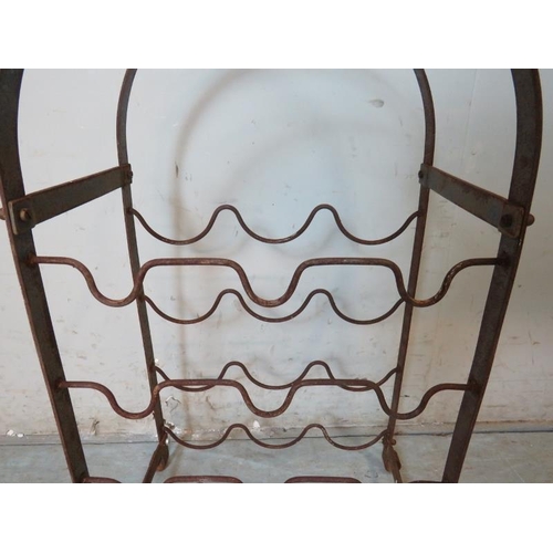 928 - A vintage wrought iron arched freestanding wine rack of good patina, raised on scrolled feet. Holds ... 