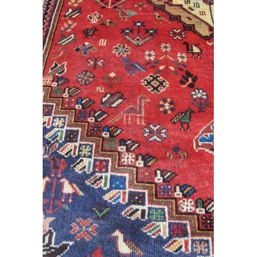 956 - A good antique Qashqai rug, a central motif in cream on a main body of claret ground with stylised b... 