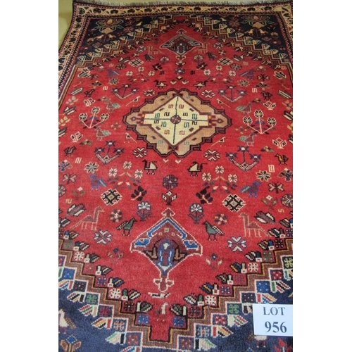 956 - A good antique Qashqai rug, a central motif in cream on a main body of claret ground with stylised b... 