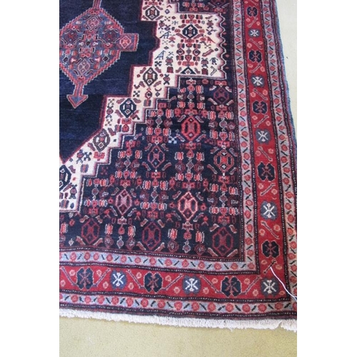 959 - An antique Persian Senneh rug with a deep rich central motif highlighted on a cream ground with styl... 