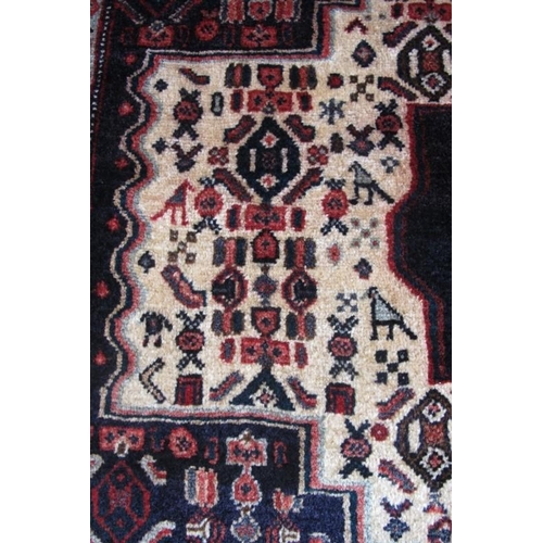 959 - An antique Persian Senneh rug with a deep rich central motif highlighted on a cream ground with styl... 