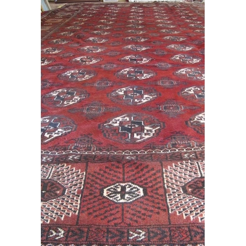 961 - An impressive Turkoman carpet rich burgundy ground with repeated pattern highlighted in cream. 395cm... 