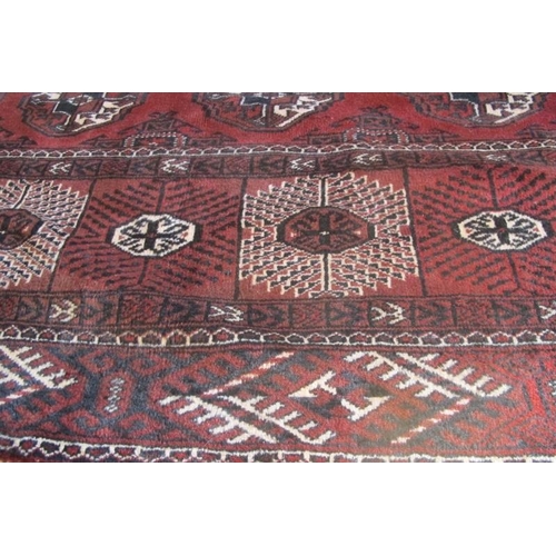 961 - An impressive Turkoman carpet rich burgundy ground with repeated pattern highlighted in cream. 395cm... 