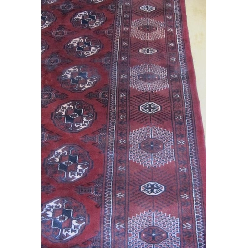 961 - An impressive Turkoman carpet rich burgundy ground with repeated pattern highlighted in cream. 395cm... 