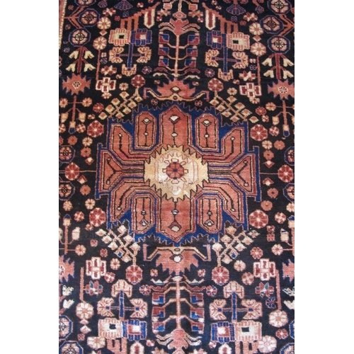 963 - An antique Nahawand carpet. A central patterned motif set on a deep rich black ground softened by re... 