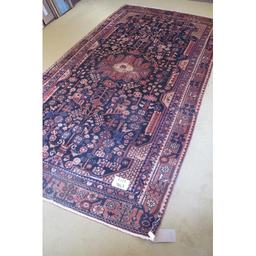 963 - An antique Nahawand carpet. A central patterned motif set on a deep rich black ground softened by re... 