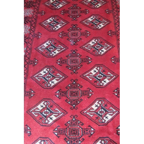 966 - A fine Persian Turkman runner repeated pattern highlighted in cream on claret ground. 305cm x 82cm.