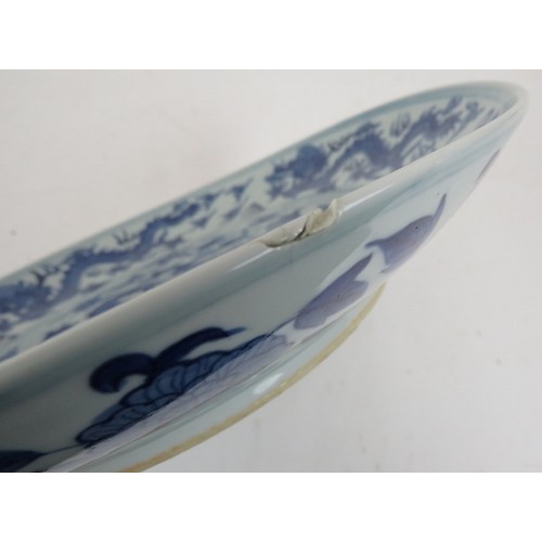 15 - An antique Chinese porcelain blue and white charger depicting a pearl chasing dragon within a four d... 