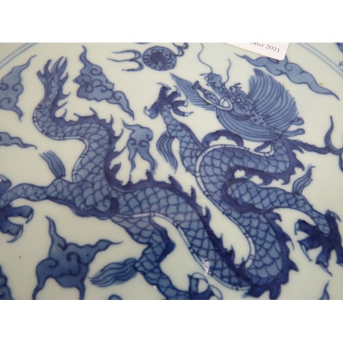 15 - An antique Chinese porcelain blue and white charger depicting a pearl chasing dragon within a four d... 