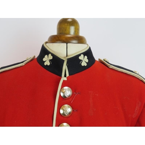 153 - An Irish Guards ceremonial scarlet tunic with Queen's crown bright buttons, mounted on a torso dummy... 