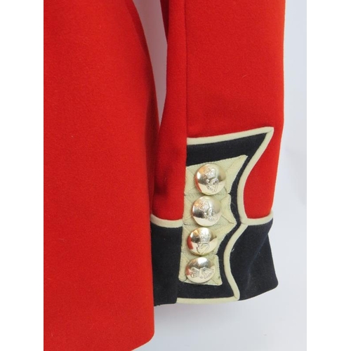 153 - An Irish Guards ceremonial scarlet tunic with Queen's crown bright buttons, mounted on a torso dummy... 