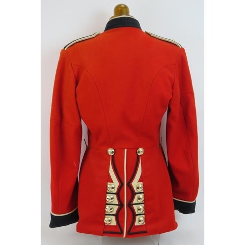 153 - An Irish Guards ceremonial scarlet tunic with Queen's crown bright buttons, mounted on a torso dummy... 