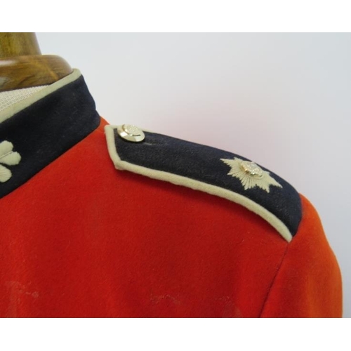 153 - An Irish Guards ceremonial scarlet tunic with Queen's crown bright buttons, mounted on a torso dummy... 