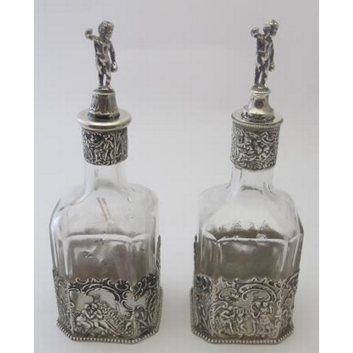 343 - A pair of German silver mounted glass bottles. The casing decorated with figures & musicians and sto... 