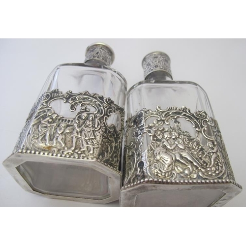 343 - A pair of German silver mounted glass bottles. The casing decorated with figures & musicians and sto... 