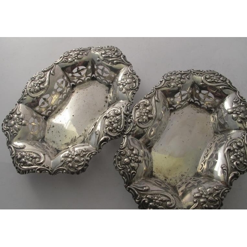 464 - A pair of oval silver bon bon dishes, heavily embossed with scrolls & flowers and pierced decoration... 