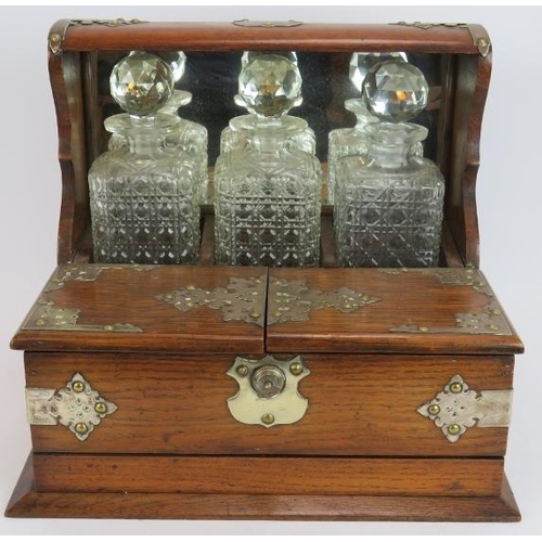 47 - A late 19th century oak tantalus box with three decanters, silver plated mounts, glass compartments ... 