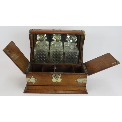 47 - A late 19th century oak tantalus box with three decanters, silver plated mounts, glass compartments ... 