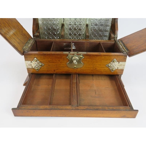 47 - A late 19th century oak tantalus box with three decanters, silver plated mounts, glass compartments ... 