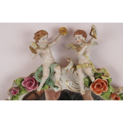 52 - A German porcelain Rococo style mirror decorated with various Putti and roses. Bears the mark of Pla... 