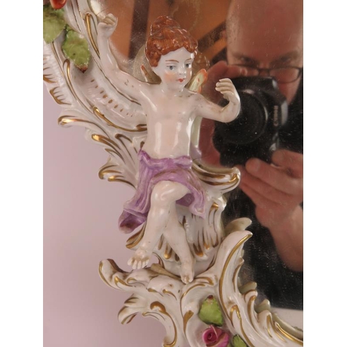 52 - A German porcelain Rococo style mirror decorated with various Putti and roses. Bears the mark of Pla... 