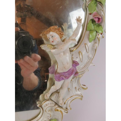 52 - A German porcelain Rococo style mirror decorated with various Putti and roses. Bears the mark of Pla... 