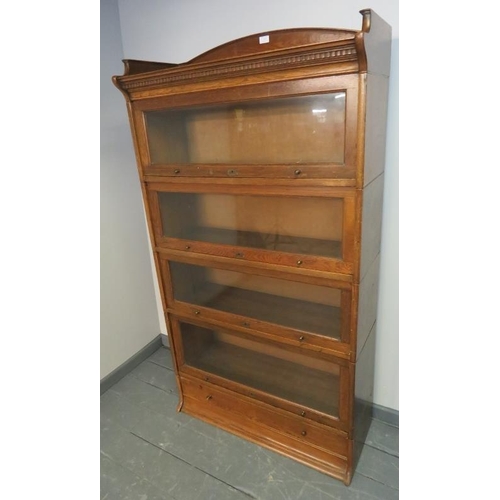 703 - A 1920s medium oak four tier stacking glazed bookcase by Lebus, with ¾ gallery and dentil cornice, o... 