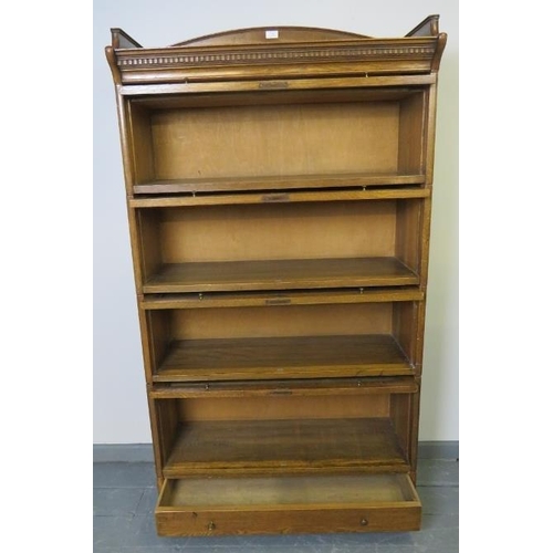 703 - A 1920s medium oak four tier stacking glazed bookcase by Lebus, with ¾ gallery and dentil cornice, o... 