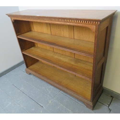 733 - An Edwardian medium oak low open bookcase of two height adjustable shelves, featuring dentil cornice... 