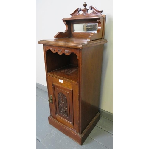 736 - An Edwardian oak bedside cabinet with upper gallery housing a bevelled mirror, and with carved panel... 