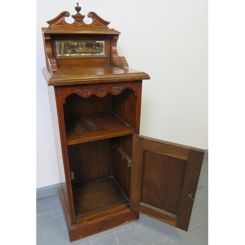 736 - An Edwardian oak bedside cabinet with upper gallery housing a bevelled mirror, and with carved panel... 