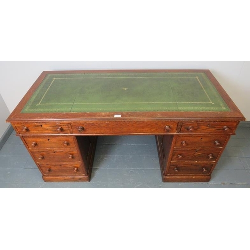 740 - A Victorian oak kneehole pedestal desk with inset gilt tooled green leather writing surface, housing... 