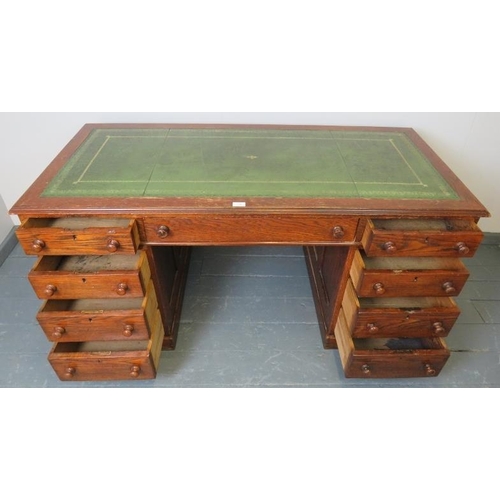 740 - A Victorian oak kneehole pedestal desk with inset gilt tooled green leather writing surface, housing... 