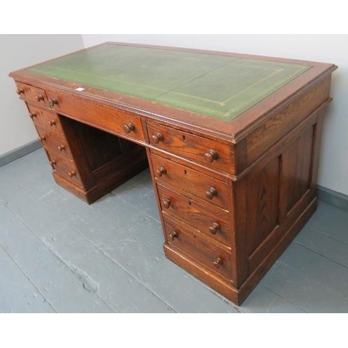 740 - A Victorian oak kneehole pedestal desk with inset gilt tooled green leather writing surface, housing... 