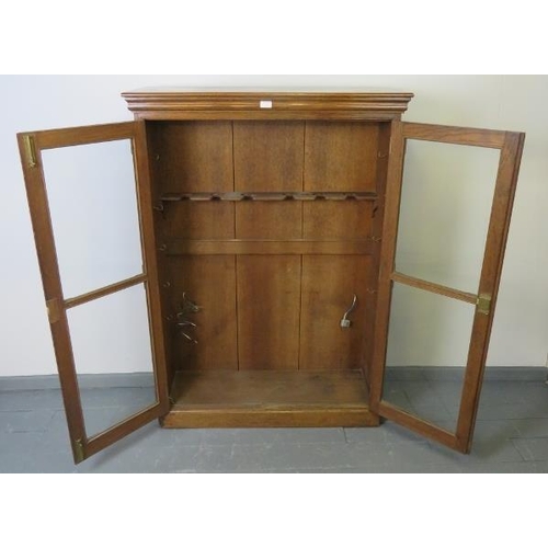 741 - A 19th century oak gun cabinet, with glazed doors opening onto a rack with provision for 6 shotguns.... 