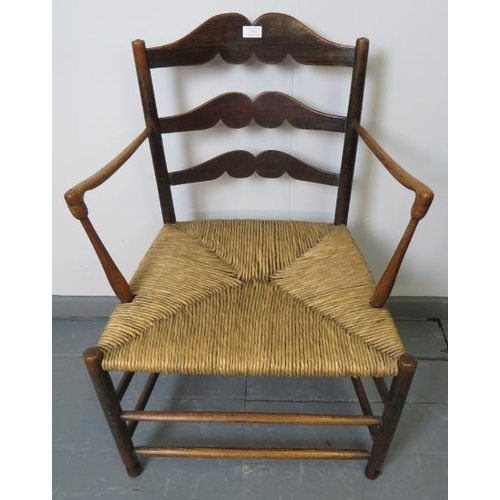 753 - A Georgian elm country made elbow chair, with shaped backrest and rush seat, on turned supports with... 