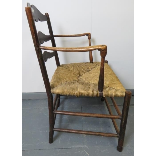 753 - A Georgian elm country made elbow chair, with shaped backrest and rush seat, on turned supports with... 