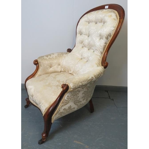 777 - A Victorian mahogany spoonback armchair upholstered in buttoned cream damask, with scrolled armrests... 