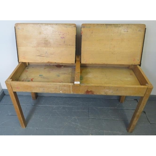 807 - A vintage beech double school desk, with individual rising lids, on square supports. 
Condition repo... 