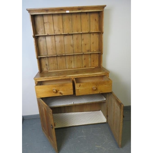 820 - An antique stripped pine kitchen dresser with plate rack shelving and two short drawers over a cupbo... 