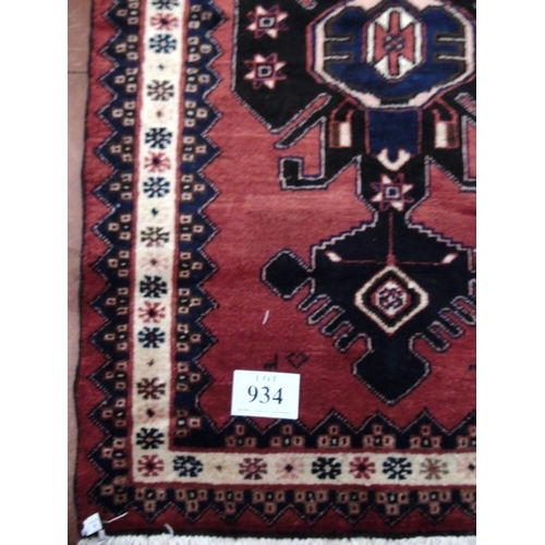 934 - A Persian rug on red ground with central blue/black motif. 150x100.