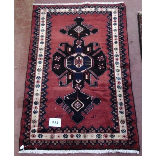 934 - A Persian rug on red ground with central blue/black motif. 150x100.