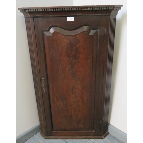 755 - A Georgian mahogany wall hanging corner cupboard with dentil cornice, flanked by reeded columns, hou... 