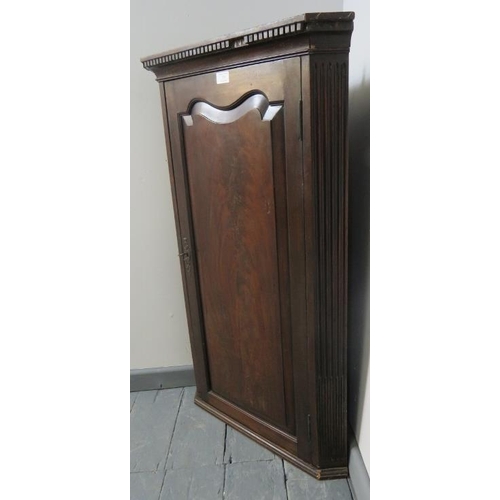 755 - A Georgian mahogany wall hanging corner cupboard with dentil cornice, flanked by reeded columns, hou... 